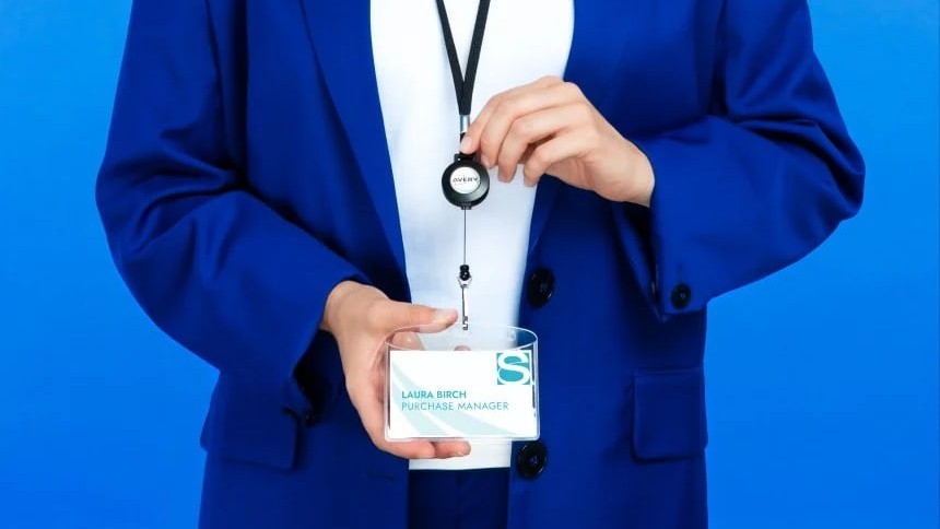 Muž v modrém obleku se šňůrkou se jmenovkou na krku