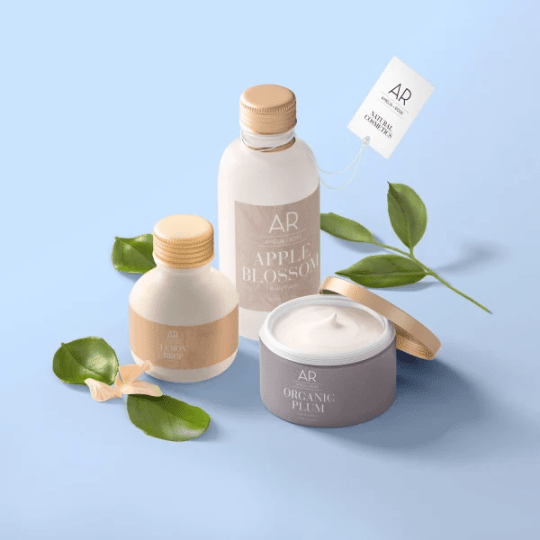Sada tří kosmetických produktů "AMELIA ROSE" na světle modrém pozadí se zelenými listy: dvě lahvičky s balzámy a kelímek s krémem "ORGANIC PLUM".