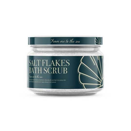 Skleněná nádoba s bílou koupelovou solí "SALT FLAKES BATH SCRUB". Etiketa je tmavě zelená s grafikou mušle.