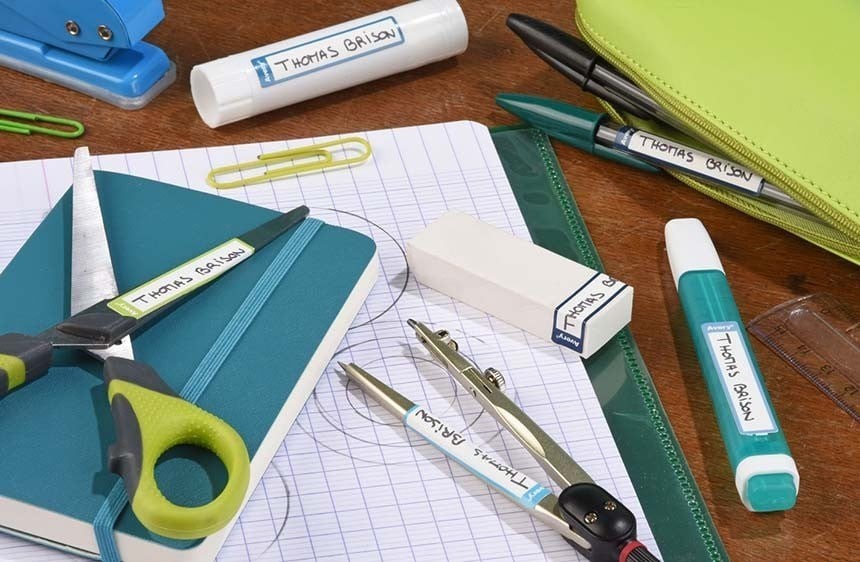 Grafika zobrazuje rozptýlené různé školní potřeby na stole, převážně v tmavě zelené barvě.