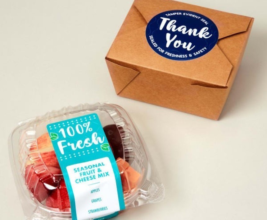 Krabička s sebou zajištěná modrou samolepkou s nápisem "Thank You" a plastová nádoba s ovocným salátem a etiketou "100% Fresh".