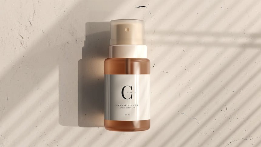 Malá hnědá lahvička se sprejem na obličejové sérum. Bílý štítek s písmenem "G" a nápisem "SERUM VISAGE". Výrobek leží na světlém, texturovaném povrchu.