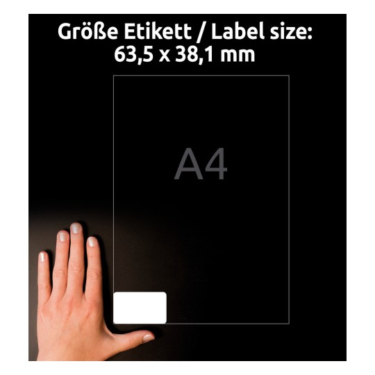 Obrázek ukazuje ruku vedle průhledného listu označeného 'A4' s rozměry '63,5 x 38,1 mm' napsanými nahoře, umístěného na černém pozadí.