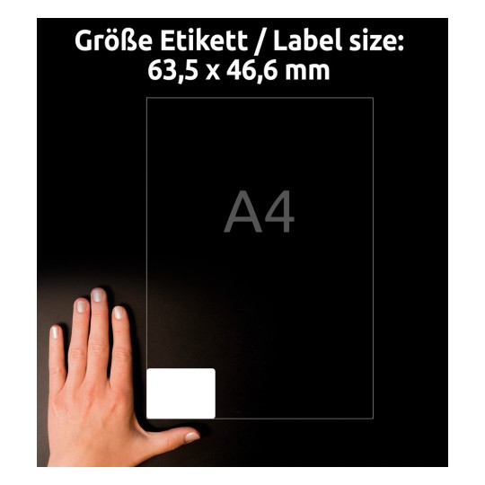 Obrázek zobrazuje ruku vedle průhledného štítku s rozměry 63,5 x 46,6 mm pro štítky velikosti A4, silueta na tmavém pozadí.