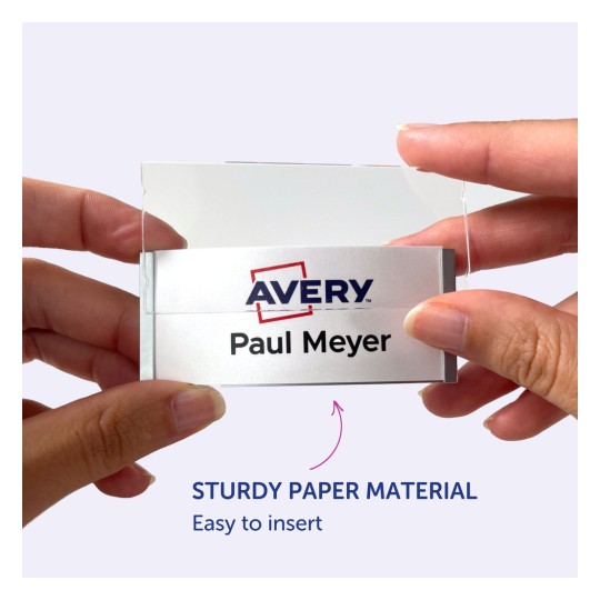 Obrázek ukazuje osobu, která drží jmenovku s logem Avery a jménem 'Paul Meyer'. Jmenovku je zřejmě snadné vložit do držáku vyrobeného z pevného papírového materiálu.