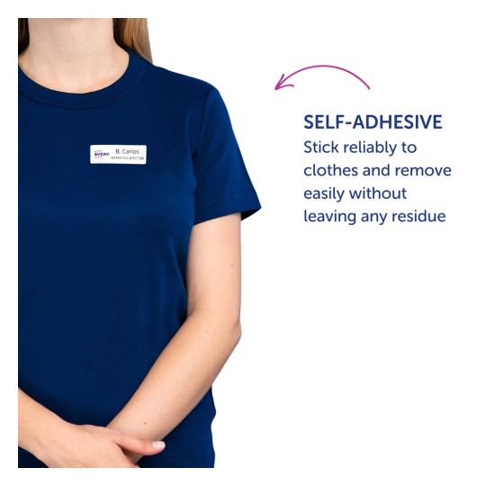 Obraz zobrazuje osobu v námořnicky modré košili se jmenovkou, na které je napsáno 'B. Carlos, ředitel marketingu.' Je tam také popis, že jmenovka je samolepící a může se spolehlivě přilepit na oblečení bez zanechání zbytku.