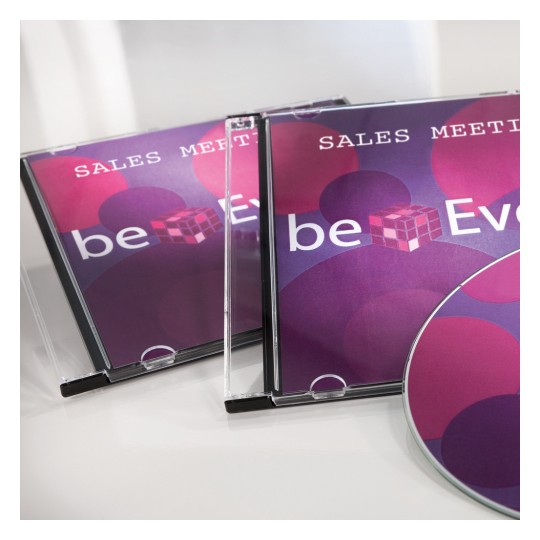 Obrázek zobrazuje dva obaly na CD s názvem 'Sales Meeting' a disk s barevným designem. Design obsahuje kruhy v odstínech růžové a fialové spolu s textem 'beEven.'