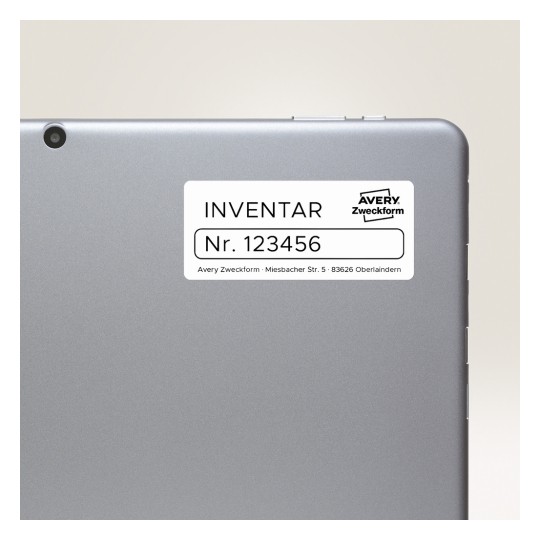 Obrázek zobrazuje zadní stranu tabletu nebo notebooku s etiketou. Na etiketě je napsáno 'INVENTAR Nr. 123456', což označuje inventární informace, a obsahuje značku 'Avery Zweckform' spolu s adresou.