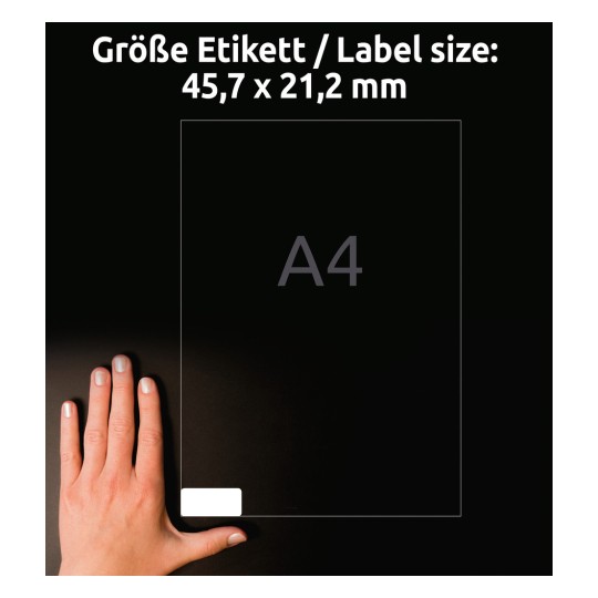 Obrázek zobrazuje ruku vedle štítku formátu A4 s rozměry 45,7 x 21,2 mm. Pozadí je tmavé, což zvyšuje viditelnost štítku a ruky.