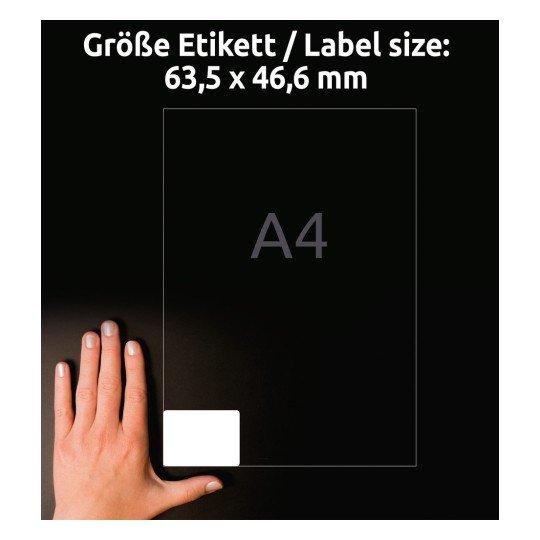 Obrázek ukazuje ruku vedle vodítka etiket označujícího velikost etikety s rozměry 63,5 x 46,6 mm označenými na pozadí listu formátu A4.