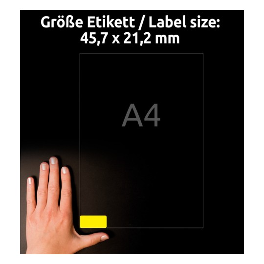 Obrázek zobrazuje ruku vedle papíru o velikosti A4 s etiketou o rozměrech 45,7 x 21,2 mm, na které je žlutá etiketa v dolním rohu.
