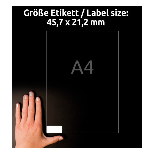 Obrázek ukazuje ruku na tmavém pozadí držící štítek s rozměry 45,7 x 21,2 mm, označený jako 'A4'.