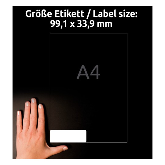 Obrázek zobrazuje ruku vedle štítku, který měří 99,1 x 33,9 mm. Štítek je zobrazen s označením velikosti A4. Pozadí je tmavé, což zdůrazňuje rozměry štítku.