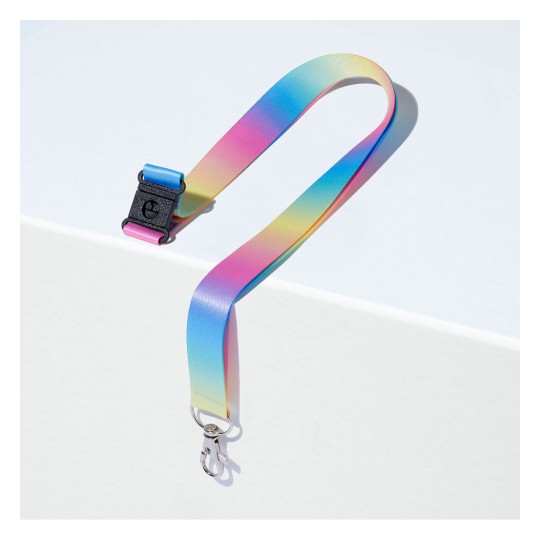 Barevný gradientní popruh s klipem v odstínech modré, růžové a žluté, umístěný na bílém povrchu.