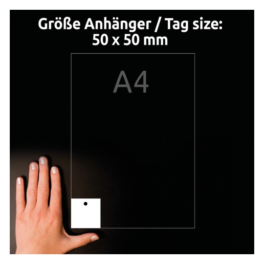 Obrázek zobrazuje ruku umístěnou vedle bílého štítku o rozměrech 50 x 50 mm, který je položen na černém pozadí. Štítek má v rohu otvor a na štítku je slabý obrys velikosti papíru A4.