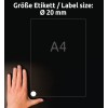 Obrázek ukazuje ruku položenou na tmavém povrchu vedle listu papíru formátu A4 s etiketou označující velikost etikety o průměru 20 mm.
