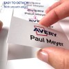 Obraz ukazuje ruku držící kartu označenou 'Avery' a 'Paul Meyer', což naznačuje, že je snadné ji oddělit díky hladkým okrajům. Na pozadí je vidět více karet.