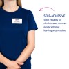 Obrázek zobrazuje osobu v námořnicky modré košili s jmenovkou, na které je napsáno 'B. Carlos, Marketingový ředitel.' Dále je tam text popisující samolepicí vlastnost jmenovky, která uvádí, že spolehlivě drží na oblečení a snadno se odstraňuje bez zanechání jakýchkoliv zbytků.
