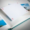 The image shows an open photo album with a blank page and some photos of landscapes. The album has a green spine and the blank page has small labels on the corners.