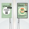 Obrázek ukazuje dvě cedule na dveřích. Levá cedule se loučí v němčině a vybízí k poskytnutí zpětné vazby prostřednictvím QR kódu. Pravá cedule vítá zákazníky, propaguje nabídku kávy s sebou se slevou 30 centů a zmiňuje týdenní nové akce na pekařské výrobky.