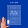 Ruka vedle listu A4 zobrazujícího mřížku obdélníků štítků 30 × 50 mm?